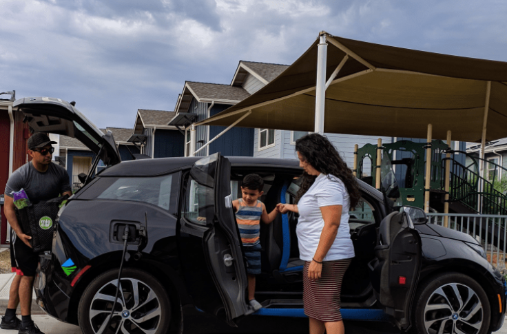 A Miocar parked at home is charging. The owners are unloading the car