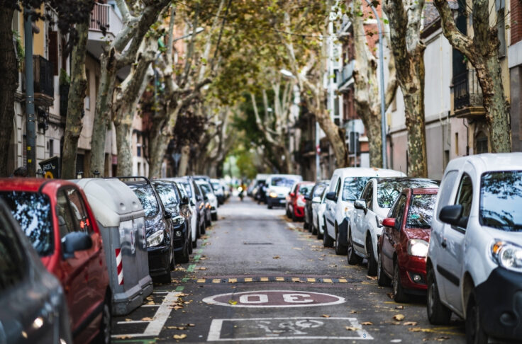 A tree-lined street with parked cars on both sides, offering ample street parking, making it a convenient spot for car share enthusiasts looking for easy curb access.