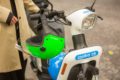 Closeup of a Cooltra moped with a greenhelmet hanging from the handlebar